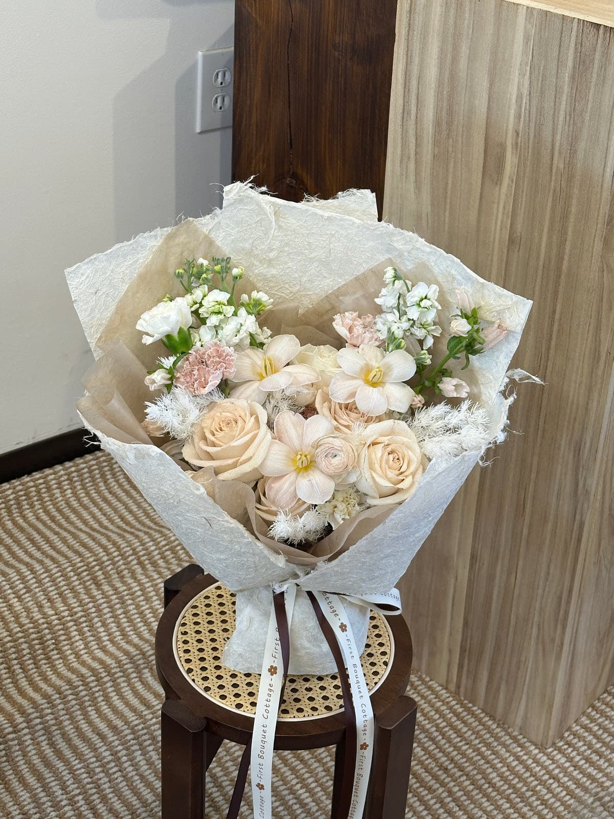 Peach roses, white lisianthus and stock in cream and kraft wrapping.